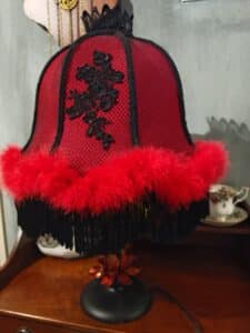 Lampe de table victorienne, abat-jour en dentelle noire sur fond rouge vif, orné de plumes, franges et d'une base florale.